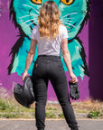 a back of a young woman motorcyclist wearing white t-shirt and black moto jeans