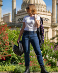 young woman wearing white t-shirt and blue jeans and holding motorcycle helmet