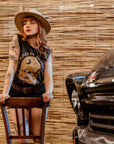 a young woman with a hat by a retro car wearing off-black tank top with brown motorcycle motive and oldies but goldies text