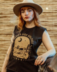 a young woman with a hat wearing off-black tank top with brown motorcycle motive and oldies but goldies text