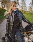 A young woman standing by her Kawasaki motorcycle wearing black leather jacket