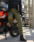 a woman leaning on her motorcycle wearing slim fit khaki green lady motorcycle jeans