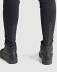 A close up of woman's shoes and legs wearing black high waist motorcycle jeans