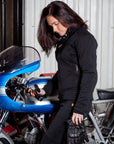 A woman standing by a motorcycle wearing women's motorcycle clothes from MotoGirl