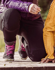 Close up of a woman's knee with black motorcycle leggings sherrie and Valerie purple jacket