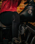 Close up of a woman's, sitting on the motorcycle and wearing black motorcycle leggings, knee