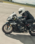 A woman racing on a motorcycle wearinh Black and red women's motorcycle racing suit from Shima