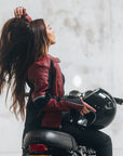 A young woman on her motorcycle wearing a red and black women's motorcycle jacket with reflectors on the sleeves.