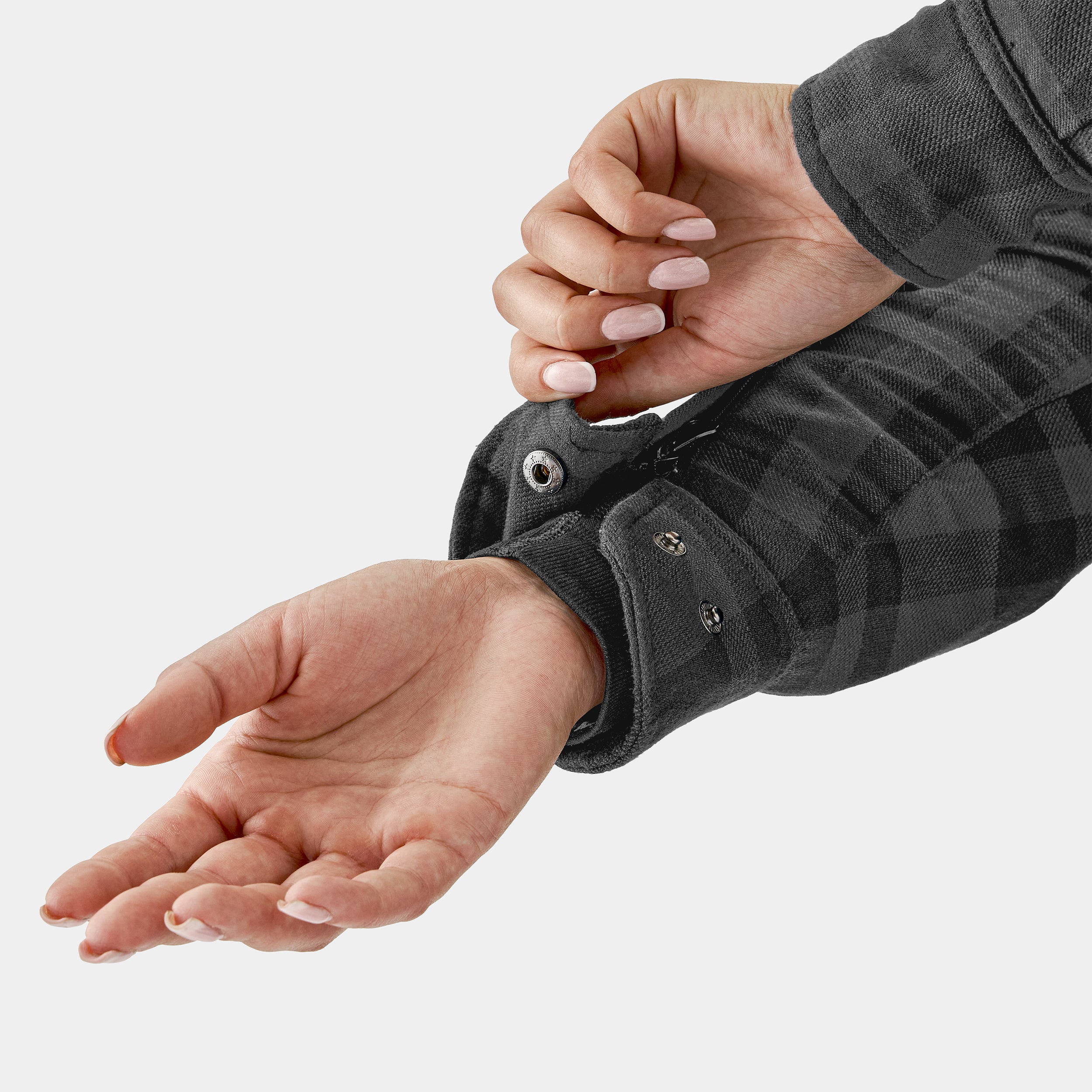 Close-up of a person wearing a dark gray plaid shirt with a focus on the sleeve and hand.