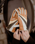 women's hands over a motorcycle gas tank while putting  on colourful leather gloves from WILDUST