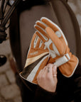 women's hands over a motorcycle gas tank while putting  on colourful leather gloves from WILDUST