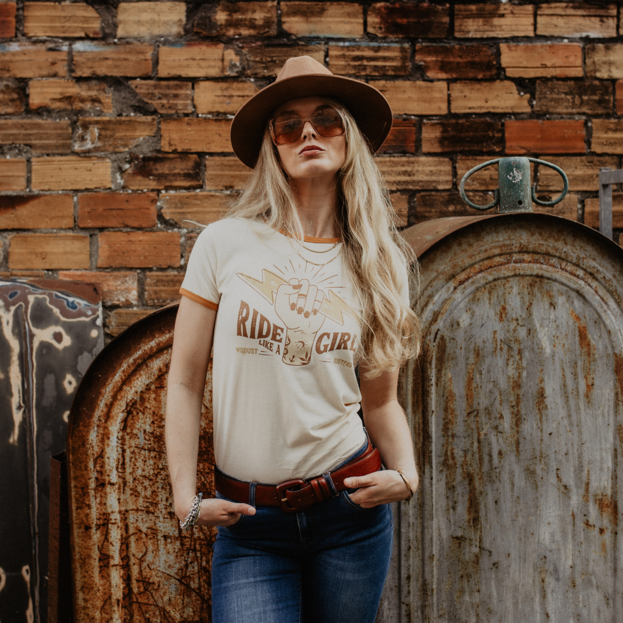 A blond woman with sunglasses and a hat wearing RIDE LIKE A GIRL retro style women's t-shirt from Wildust Sisters