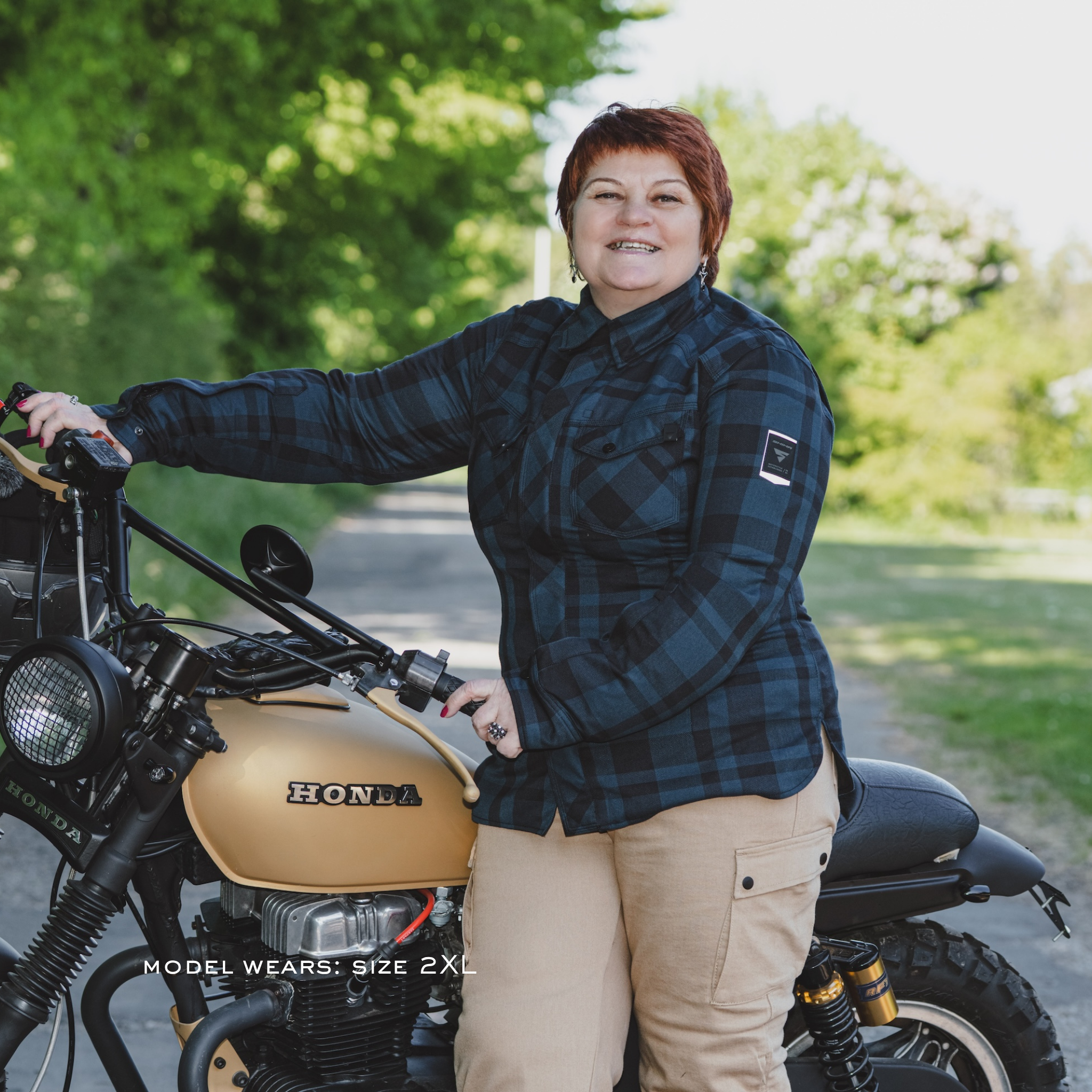Person standing next to a Honda motorcycle in a natural setting wearing blue shima renegade motorcycle shirt for women