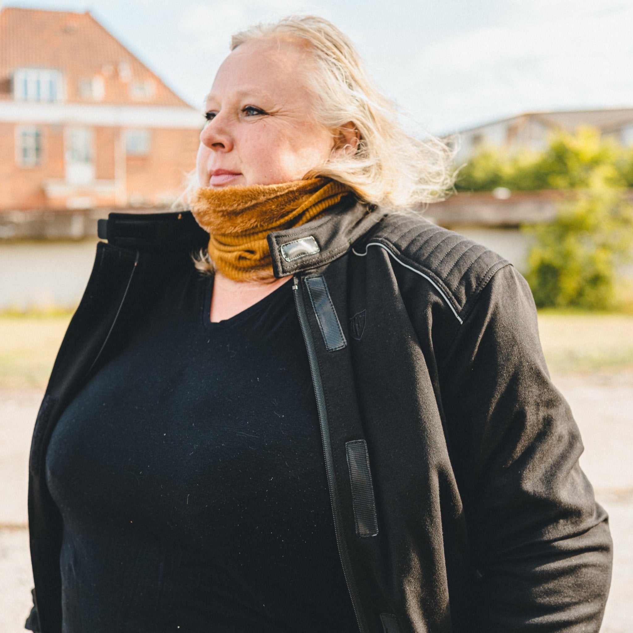 blond woman standing outside while wearing sherrie mc-jacket and a caramel color knitted neck warmer from Moto Girl. 