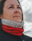 Woman standing outside wearing a black motorcycle jacket and a red knitted neck warmer from Moto Girl.