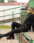 A woman wearing black boots, black mc jacket and black womens motorcycle pants with a front zip from Moto Girl 