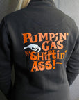 A woman wearing black lady sweatshirt with orange "pumping gas shifting ass"motive on the back