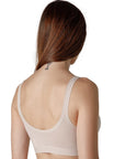 The back of a dark red-haired woman with a neck tattoo wearing a nude-colored wide-strap bralette from Tramonte.