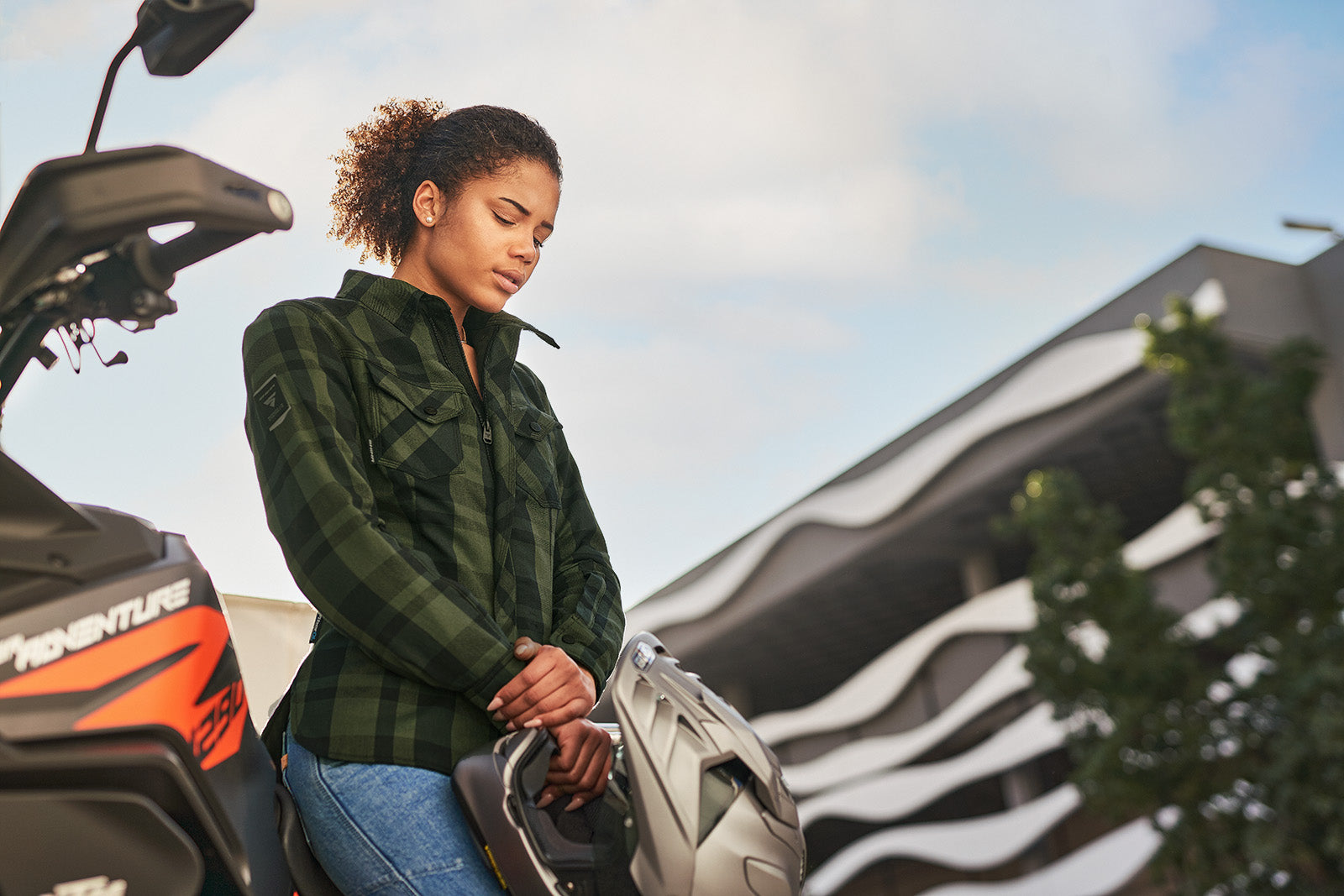Woman holding a helmet next to a motorcycle with a scenic background