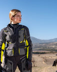 A woman standing by her mc wearing shima motorcycle touring jacket for women in black/ fluo