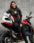 A woman on a motorcycle wearing SHIMA MOTORCYCLE LEATHER jacket IN BLACK FLUO, WHITE AND RED FLUO