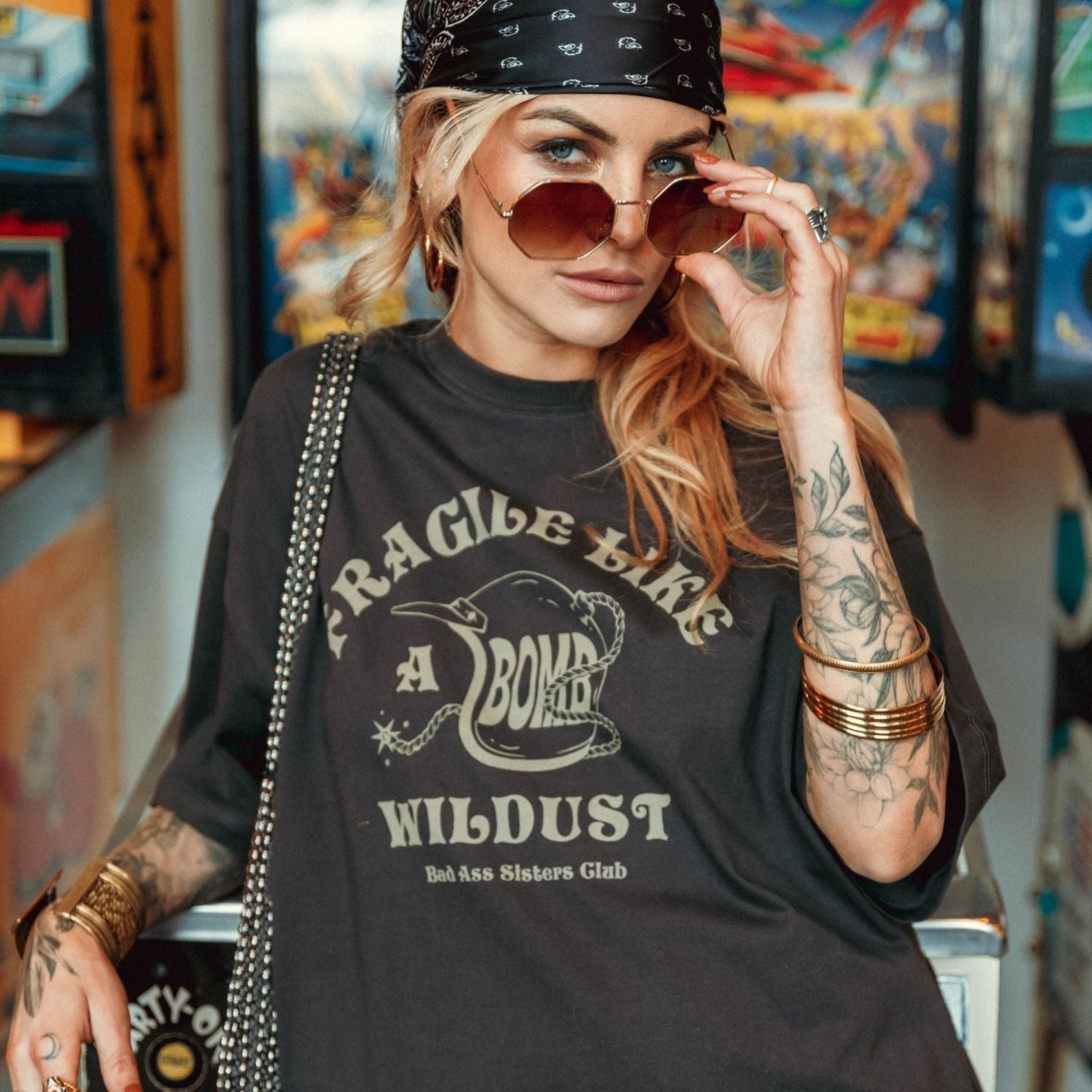 a young woman with sunglasses wearing off-black wide cut short sleeve women&#39;s motorcycle t-shirt with helmet motive and Fragile like a bomb  logo 
