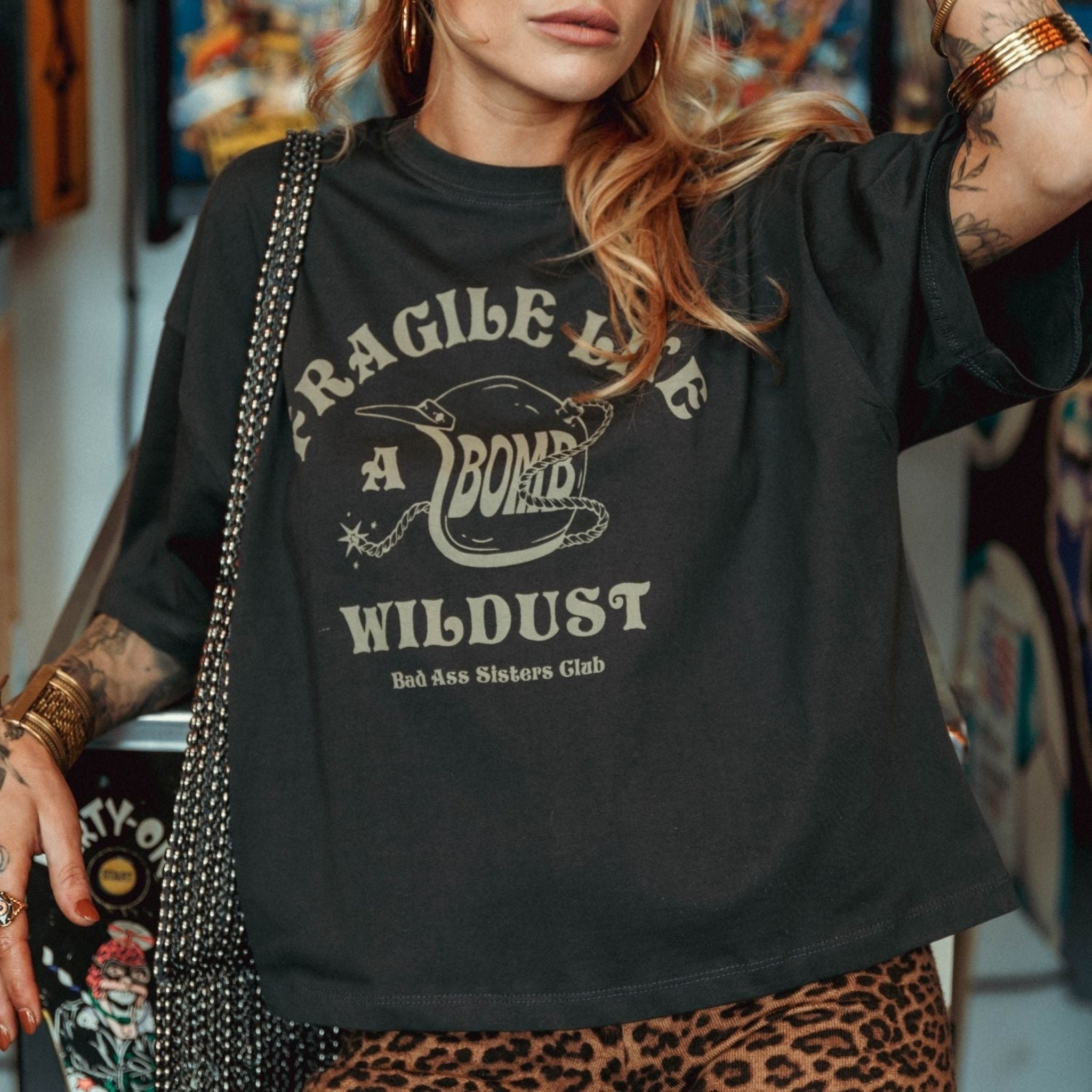 a young woman wearing off-black wide cut short sleeve women&#39;s motorcycle t-shirt with helmet motive and Fragile like a bomb  logo 