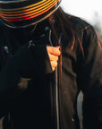 woman with a helmet zipping her Black retro style woman's motorcycle jacket with silver zip details