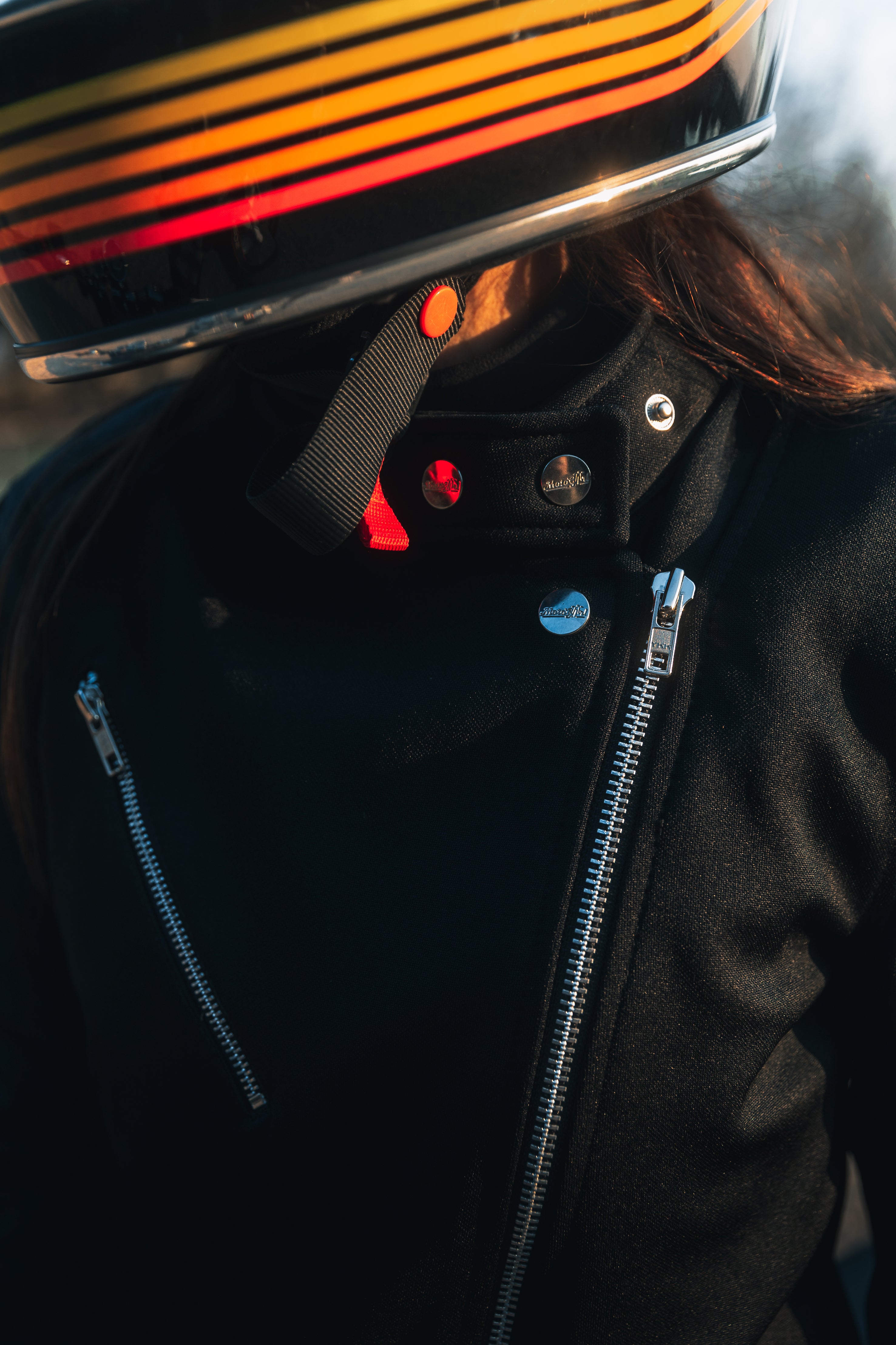 woman with a helmet wearing Black retro style woman&#39;s motorcycle jacket with silver zip details