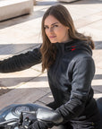 Woman in a black jacket sitting on a motorcycle outdoors