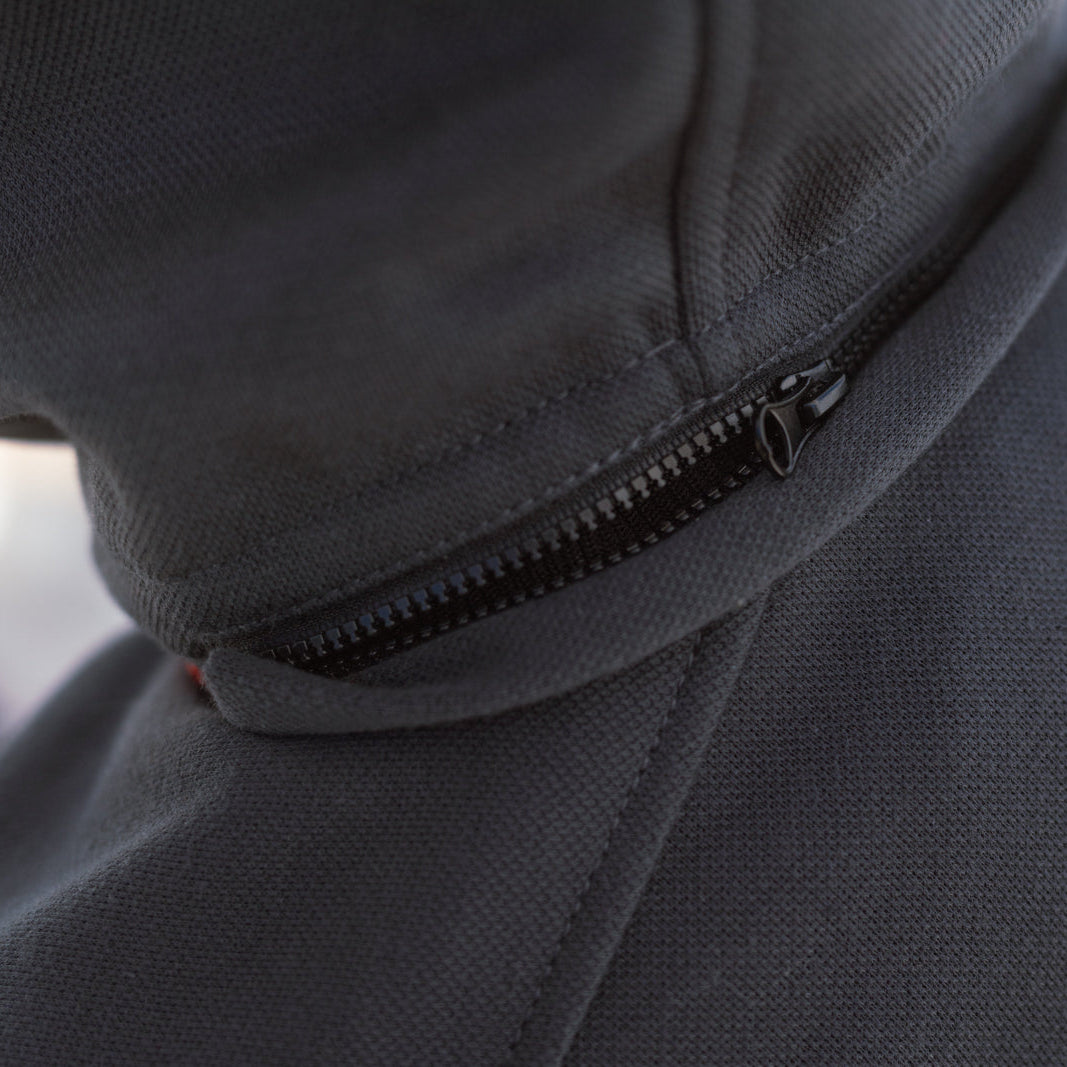 Close-up of a dark gray zippered hooded jacket or hoodie showing the zipper detail and part of a light gray geometric logo on the shoulder.
