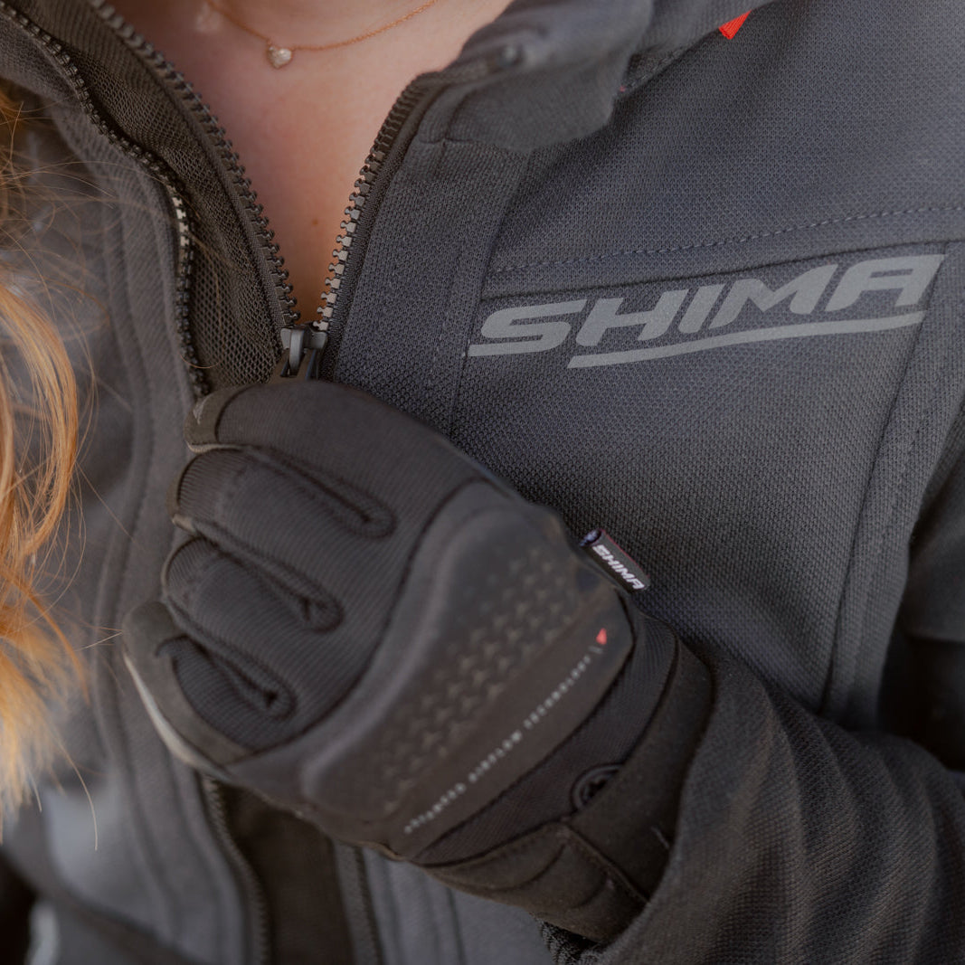 Person wearing a gray jacket with 'Shima' branding and black gloves.
