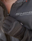 Person wearing a gray jacket with 'Shima' branding and black gloves.