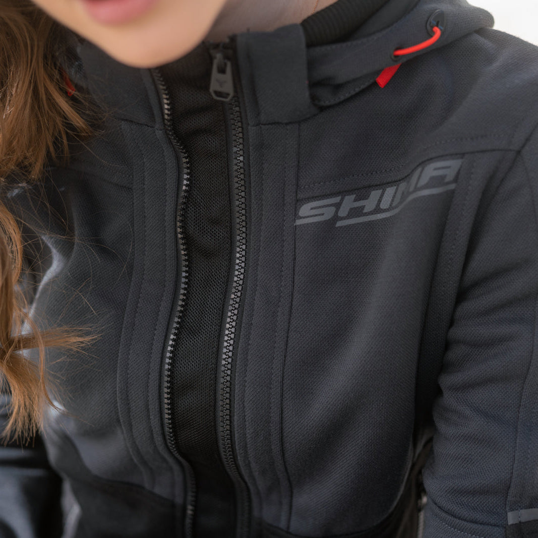 Person wearing a black jacket with 'SHINE' branding on a blurred background