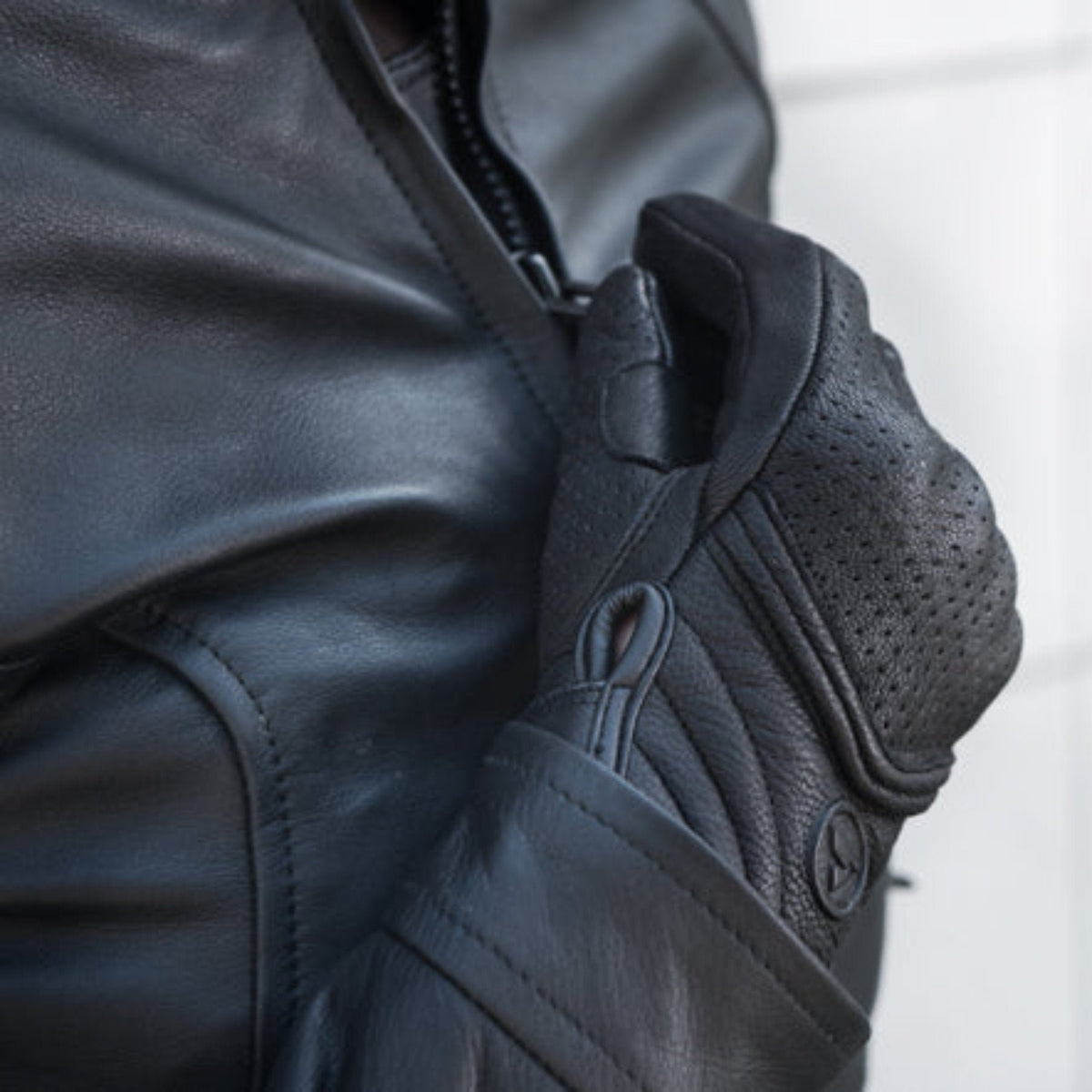 Women closing motorcycle jacket's zipper wearing black leather Shima motorcycle gloves