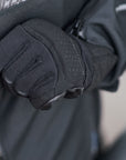 a hand wearing Black leather and textile women motorcycle glove zipping the jacket