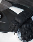 Black leather women's motorcycle gloves from Shima on a tank of a white motorcycle 