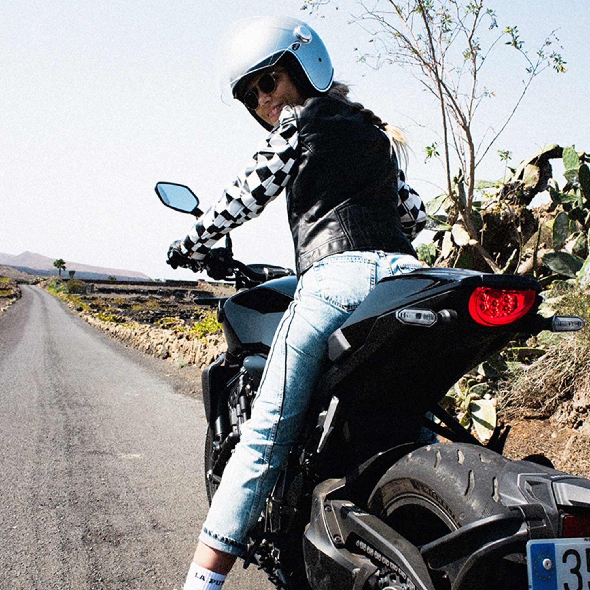 A woman on a motorcycle wearing a Chessboard design leather motorcycle jacket from eudoxie