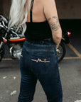 A tattooed woman on her Suzuki motorcycle wearing blue lady motorcycle jeans from Moto Girl.