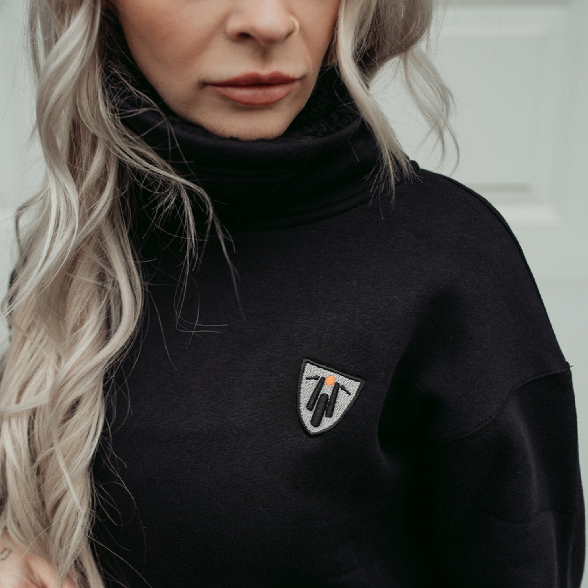 a blong young women wearing high neck black sweatshirt with motogirl logo in front