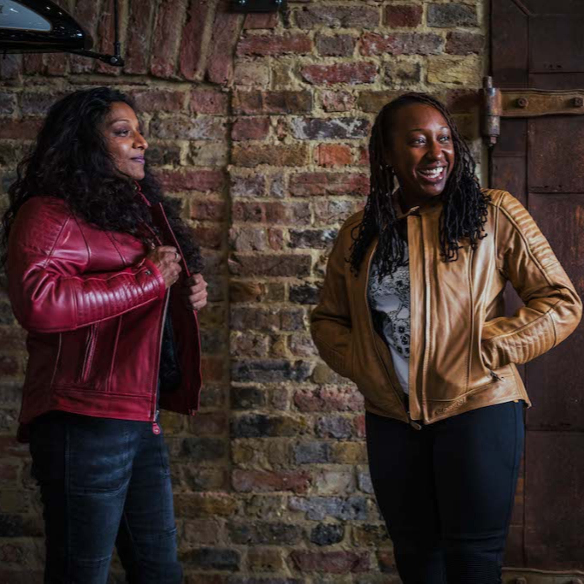 two smiling women wearing a red and a camel leather Valerie jacket from moto girl