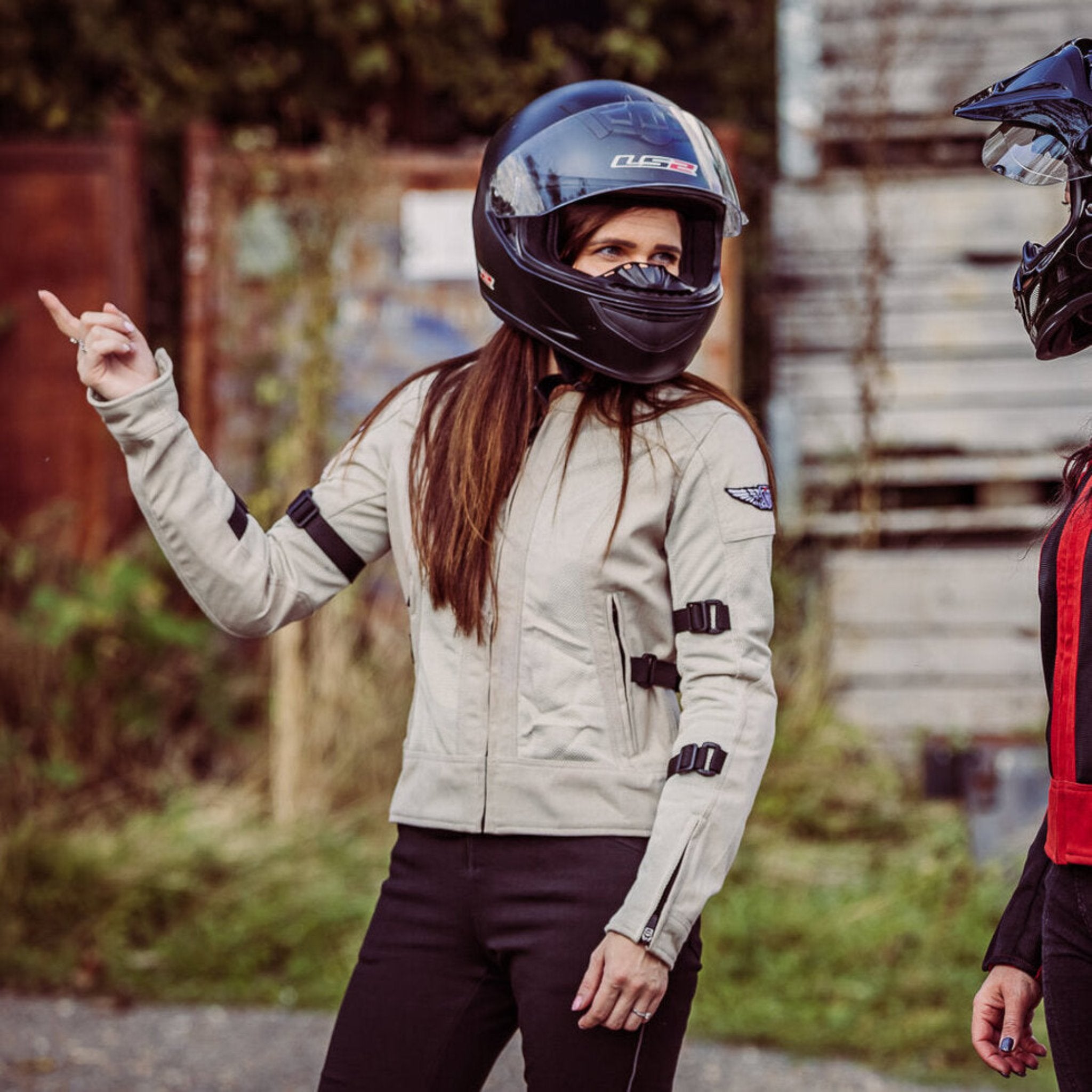 A woman with a helmet wearing  women's summer mesh motorcycle jacket from Moto Girl and pointing somewhere