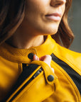 Close-up of a woman zipping up her yellow black motorcycle jacket.