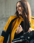 A young woman on her motorcycle wearing a red and black women's motorcycle jacket with reflectors on the sleeves.