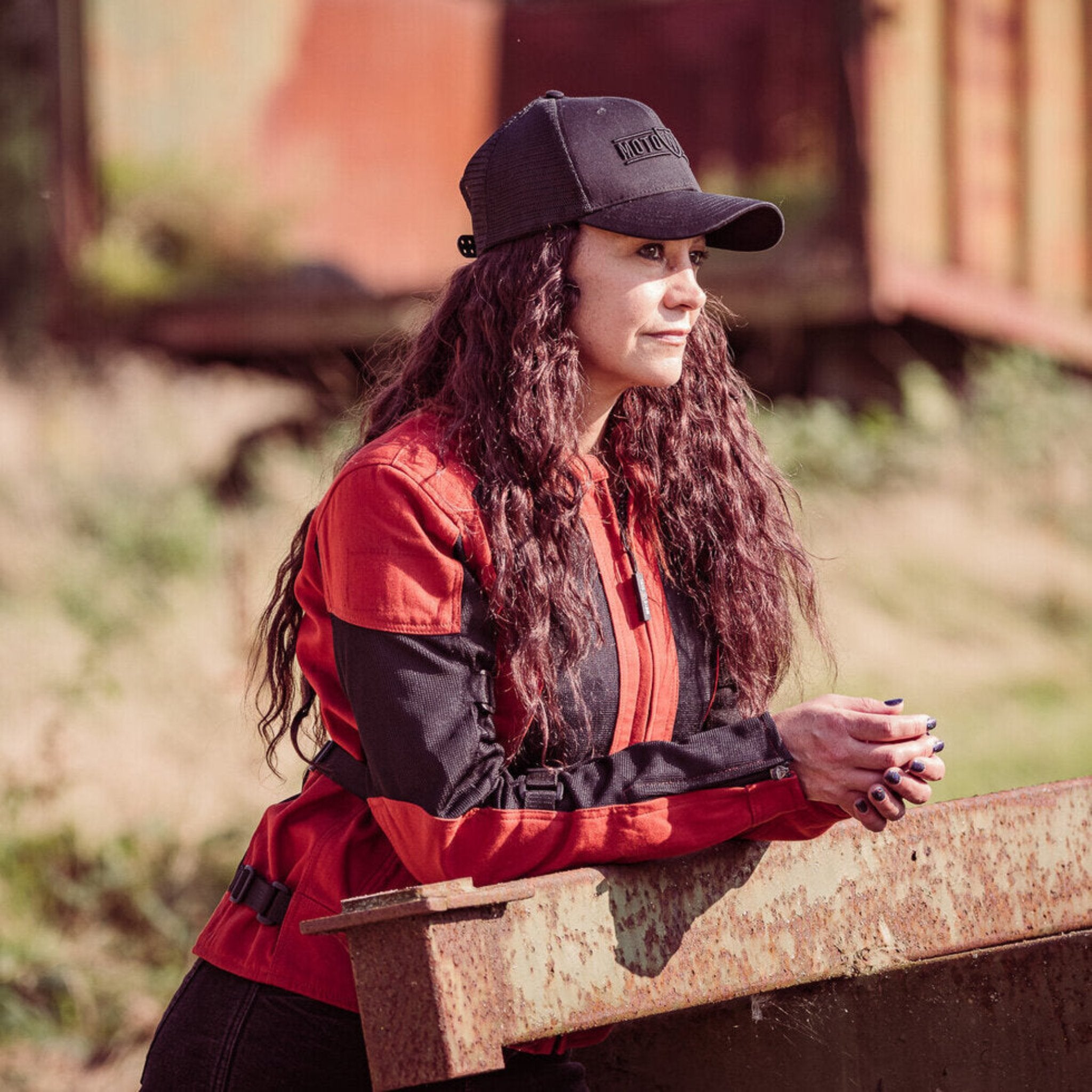 a  woman with the cap wearing red and black women's motorcycle summer jacket from Moto Girl 